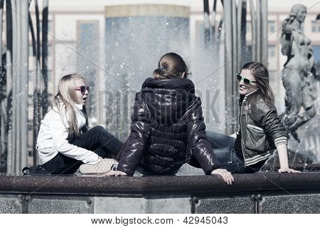 Goup of teenage girls sitting against a city fountain