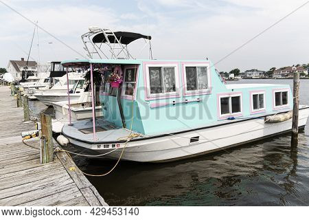 Babylon, New York, Usa - 29 June 2019: A Houseboat Pluged Into The Electric Moored At A Dock Painted