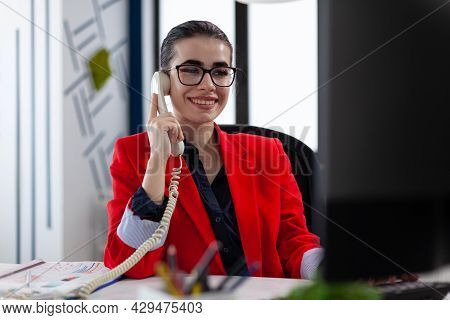 Businesswoman Having A Phone Coversation With Financial Adviser Sitting At Desk Looking At Charts On