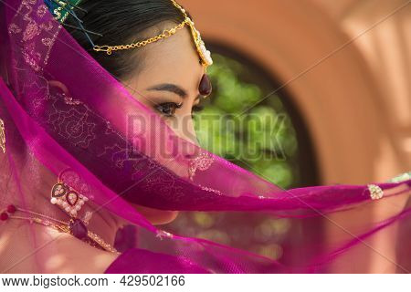 Portrait Asian Woman In A Margenta Indian Tradition Sari, She Is Looking At A Camera With Orange Wal