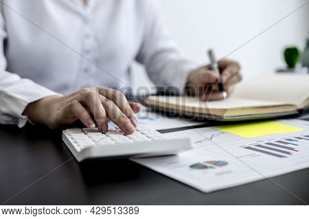 An Accounting Businesswoman Pressing The White Calculator And Taking Notes In Her Notebook, She Was