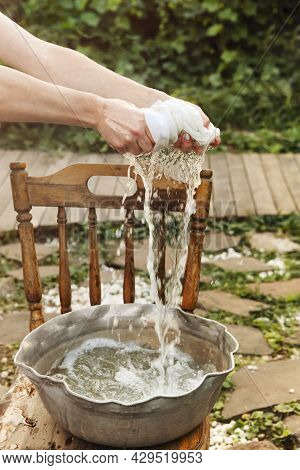 Cropped Shot Of Woman Washing Dirty Clothing In Metal Basin On Sunny Day Near Home, Female Squeezing