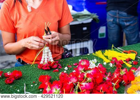 Asian Woman Staff Is Stringing Flower Garlands In Flower Shop
