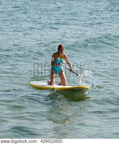 A Teenage Girl Rowing An Oar On A Sup Board