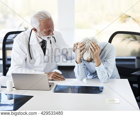 Senior Doctor Listening To His Sad Retiree Patient In Hospital