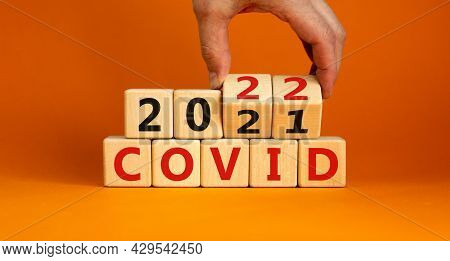 Symbol Of Covid-19 Pandemic In 2022. Doctor Turns Wooden Cubes And Changes Words 'covid 2021' To 'co