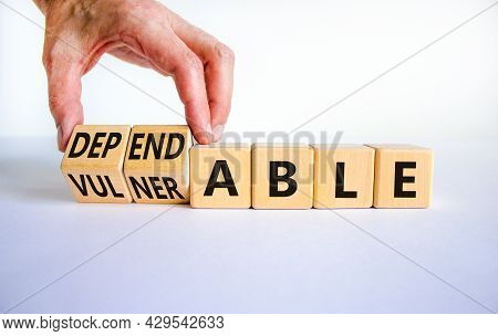 Vulnerable Or Dependable Symbol. Businessman Turns Wooden Cubes And Changes The Word Vulnerable To D