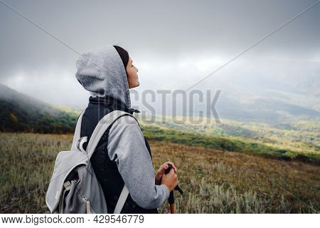 Asian Travel Woman Stands By The Mountain. Cold Weather, Fog On The Hills. Autumn Hike. The Beginnin