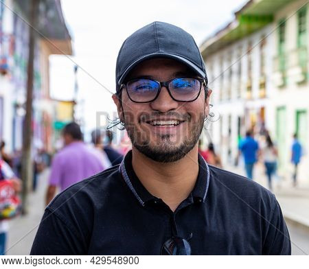 Portrait Laughing Latino Young Man With Cap And Eyeglasses In A Street Of A Town In Filandia Quindio