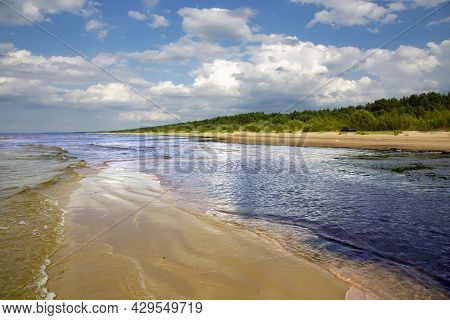 Cumulus Clouds Over Wild Sandy Coast Reflected In A Small Shallow Of The Baltic Sea In Vecaki, Latvi