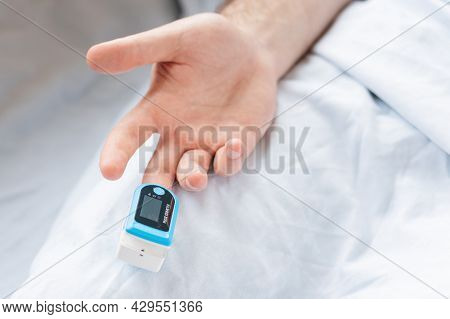 Determination Of Oxygen In The Blood. Male Hand With A Pulse Oximeter On The Middle Finger, Close-up