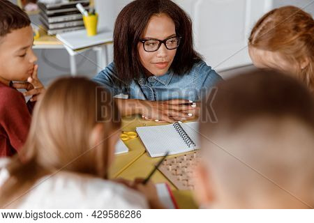Teacher With Glasses Looking At Schoolchildren During Lesson