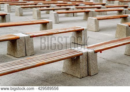 Empty Benches Made Of Wood And Concrete With Traces Of Restrictive Tapes. Standing In The Flying Str