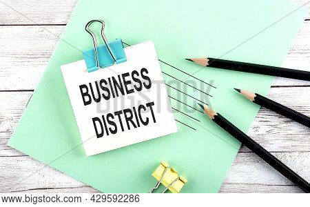 Text Business Districk On The Short Note With Pencils On Wooden Background