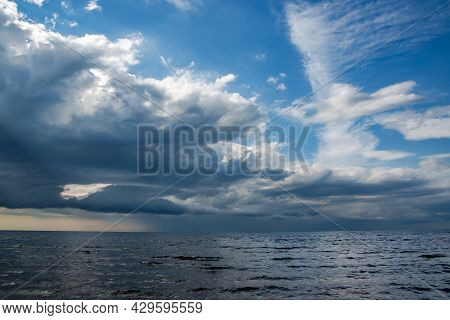 Rainy Dark Clouds During At Sunset At Baltic Sea. Dark Sea Water And Heavy Beautiful Grey Clouds In 