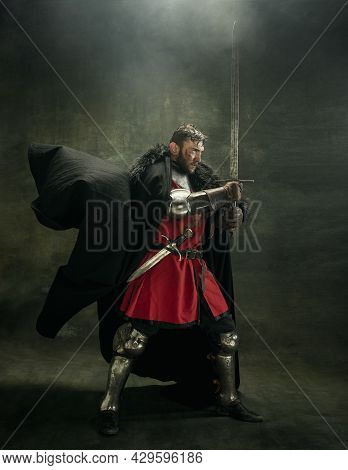 One Brutal Bearded Man, Medeival Warrior Or Knight With Dirty Wounded Face Holding Sword. Full Lengt