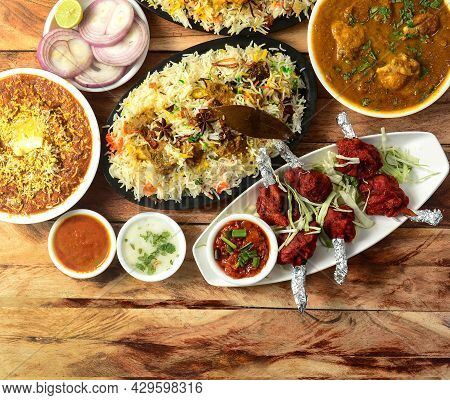 Assorted Indian Food On Wooden Background. Thalaseri Mutton Biryani,chicken Lollipop, Butter Chicken