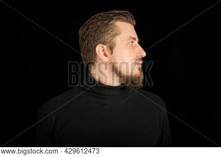 Cute Bearded Man, Half-face Portrait, Black Background. Young Guy In Black Polo Neck Sweater. Confid
