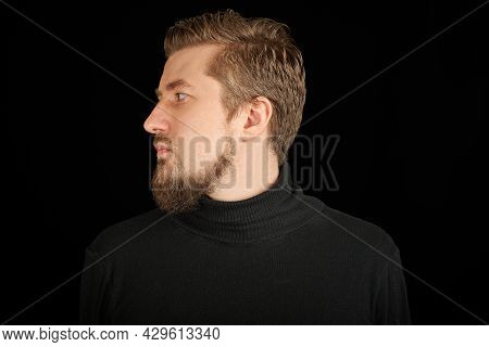 Cute Bearded Man, Half-face Portrait, Black Background. Young Guy In Black Polo Neck Sweater. Confid