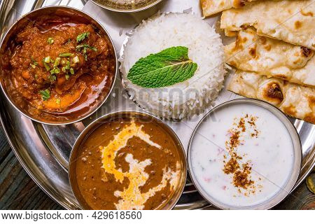 Assorted indian food set on wooden background. Dishes and appetisers of indeed cuisine, rice, lentils, paneer, samosa, spices, masala. Bowls and plates with indian food