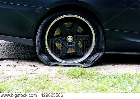 Punctured Wheel Of A Modern Car On The Road. Car Tire Puncture.