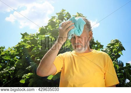 Senior Man With Towel Suffering From Heat Stroke Outdoors, Space For Text