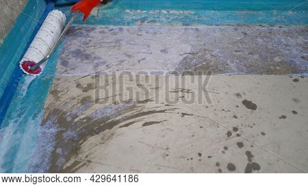 Priming The Floor With A Roller. Finishing Works - A Working Roller Primer Floors For Laying Tiles. 