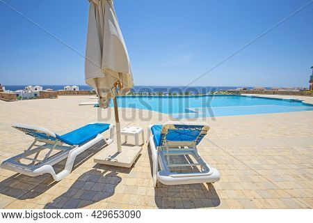 Large Outdoor Swimming Pool At A Luxury Tropical Hotel Resort With Sun Lounger Beds And Sea View