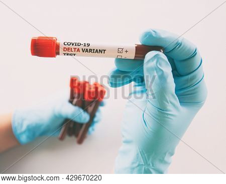 The nurce holding  tube of blood test with the label Covid-19 DELTA Variant.