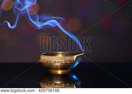 Blown Out Diya On Dark Background With Blurred Lights. Diwali Lamp