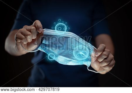 Close Up Shot Of Hands Holding Protective Face Mask With Virus Hologram Effect.
