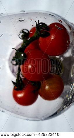 Cherry Tomatoes Behind Wet Glass On A White Background