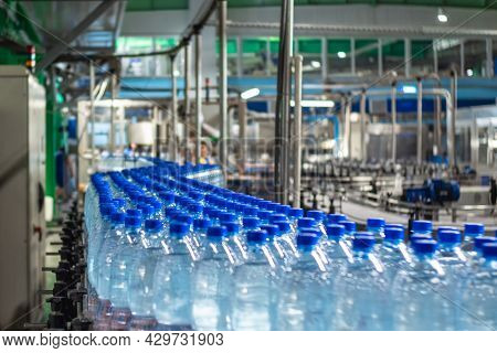 Blue Plastic Bottles In Three Rows With Clean Drinking Water On A Conveyor Belt At A Mineral Water P