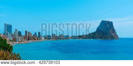 a view over Calp, in the Valencian Community, Spain, highlighting the apartment towers and the Penon de Ifac promontory on the right, in a panoramic format to use as web banner or header