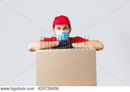 Packages And Parcels Delivery, Covid-19 Quarantine And Transfer Orders. Young Courier In Red Uniform