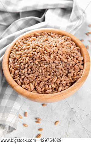 Wholegrain Uncooked Raw Spelt Farro In Wooden Bowl On Grey Stone Table Background, Food Cereal Backg