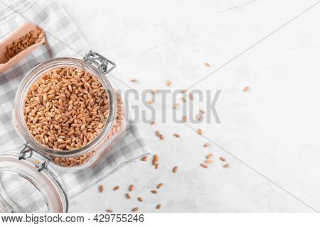 Wholegrain Uncooked Raw Spelt Farro In Glass Jar On Grey Stone Table Background, Food Cereal Backgro