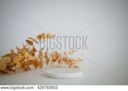 Marble Podium With Golden Leaves On The White Background. Podium For Product, Cosmetic Presentation.