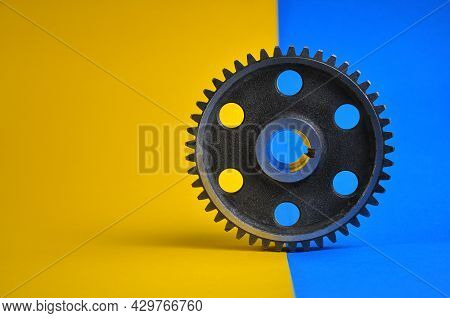 Gear Wheel On A Blue-yellow Background. Spare Parts.