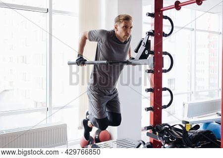 Athlete Man In The Gym Doing Elevations. Caucasian Male Training In The Gym During The Day