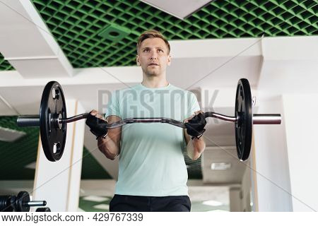 Athlete Man Lifting Barbells Working Out With Curl Bar In The Gym Doing Elevations. Caucasian Male T