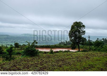 Scenic View Of Small Pond Full Of Brown Color Water In The Middle Of The Farmland Or Agricultural Fi