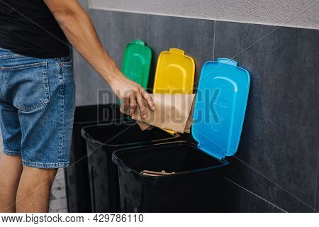 Close-up Of Man Throwing Peace Of Cardboard In Recycling Bins. Humen Hand Holding Paper Near The Pla