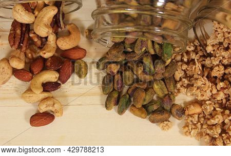 Pistachios And Mixed Nuts With Organic Granola On Wooden Table