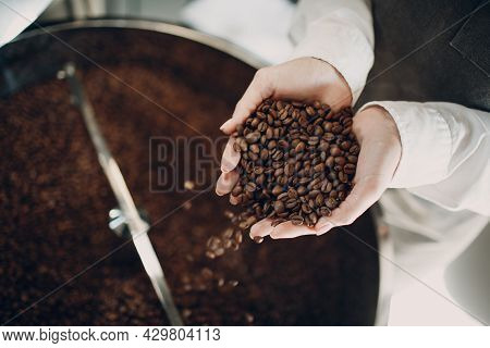 Coffee Cooling In Roaster Machine At Coffee Roasting Process. Young Woman Worker Barista Pours Coffe