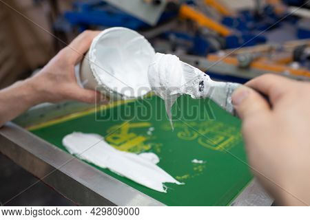 Serigraphy Silk Screen Print Process At Clothes Factory. Frame, Squeegee And Plastisol Color Paints.