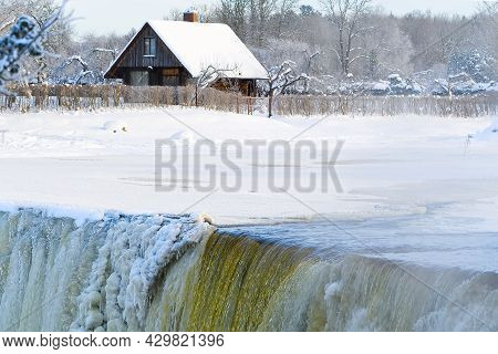 Frozen Beautiful Waterfall Jagala Under The Sunrise Lights In Winter, Reflection In River. Estonia.