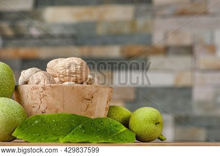 Walnut. Walnut Fruits Lie In A Wooden Saucer. Nearby Are Green Leaves And Unripe Walnut Fruits. Bann