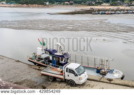 Taean, South Korea; July 30,2021: Truck Parked On Concrete Dock Beside Moored Fishing Trawler.