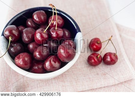 Bowl Of Cherries On Pink Linen Napkin. Top View. Sweet, Ripe Berries With Water Drops. Summer Harves